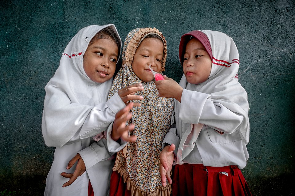 Pupils sharing an ice lollipop during playtime break (Rustam Awat/AGORA images)